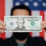Why So Many Americans Are Drowning in Debt (And How Discipline Still Wins) Person holding a twenty dollar bill in front of an American flag
