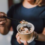 The Simple Habit That Helps Your Gut Handle Stress Better Person holding a cup of oatmeal with a spoon