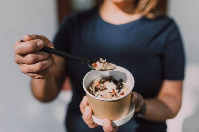 Person holding a cup of oatmeal with a spoon