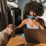 How Simple Morning Routines Help Reduce Anxiety and Mental Overload Woman sipping coffee while petting her dog in a home office setting