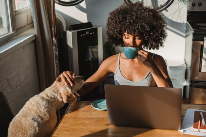 pexels-samson-katt-5256142 (1).jpg Woman sipping coffee while petting her dog in a home office setting