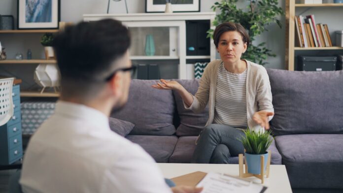 A woman expressing herself during a therapy session with a male therapist in a modern setting