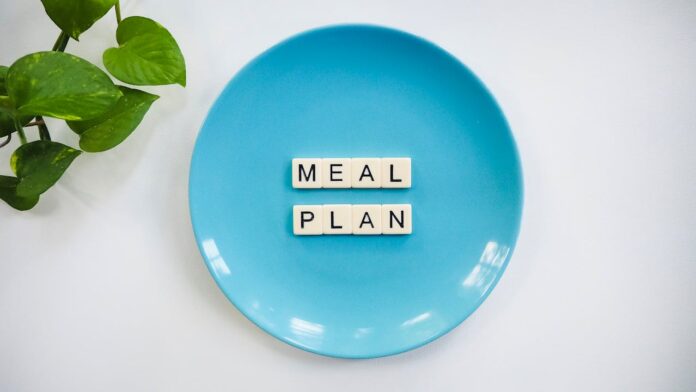 Blue plate with scrabble tiles spelling 'MEAL PLAN' and a green plant
